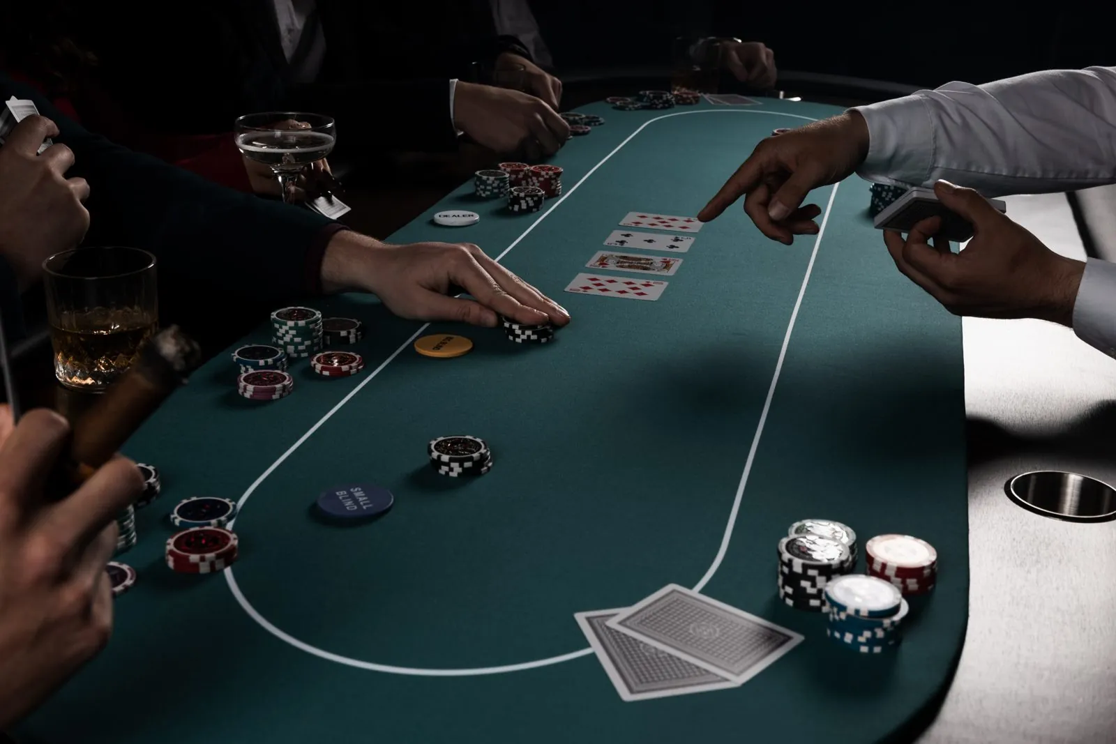 Goście przy stole pokerowym, krupier wskazuje karty